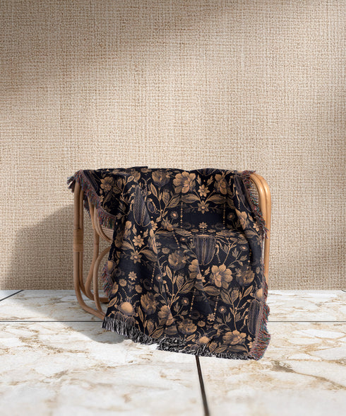 Black cotton throw blanket featuring woven bronze beetles and botanical motifs with multicolored fringe trim.